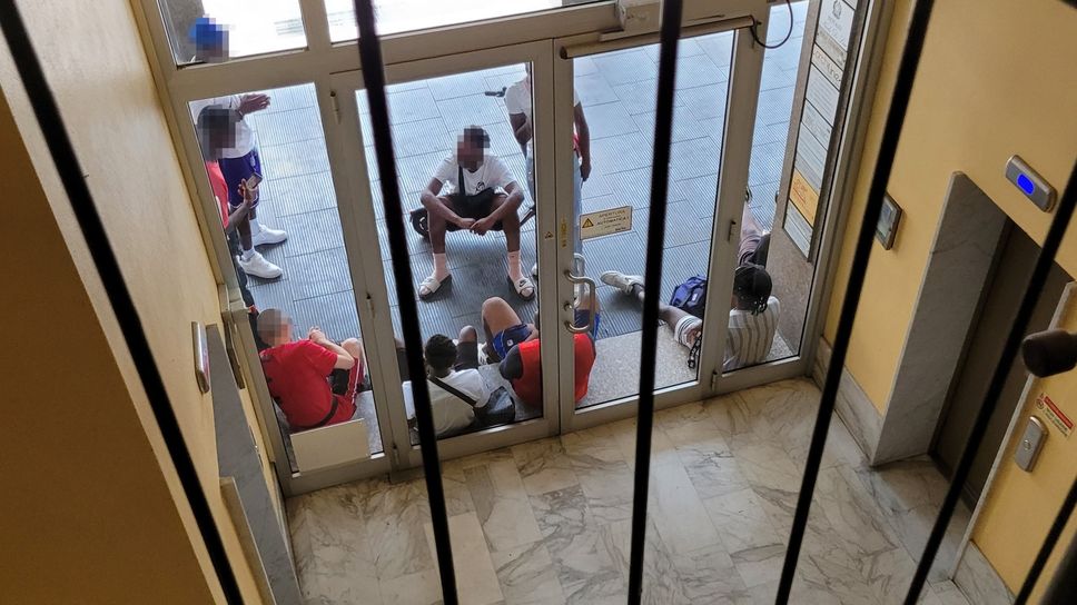 L’ingresso al condominio di piazza Affari: la porta è circondata dal gruppetto di ragazzi L’ingresso al condominio di piazza Affari: la porta è circondata dal gruppetto di ragazzi
