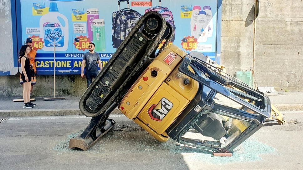 Escavatore scivola dal cassone di un camion in transito a Sondrio